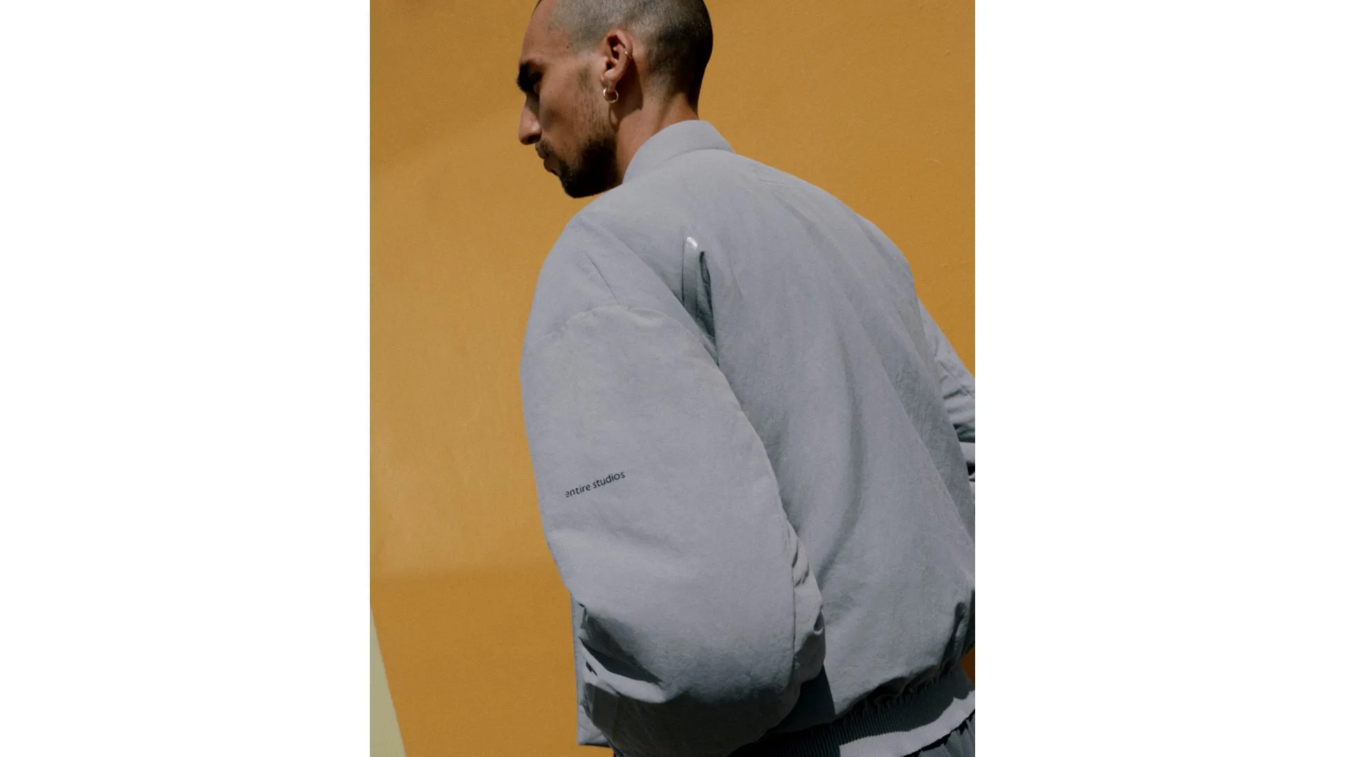 รายละเอียดด้านหลังเสื้อบอมเบอร์สีเทา adidas x Entire Studios